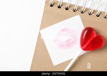 Lopop en forme de coeur, carnet et note en papier avec liseré sur fond blanc, couché à plat. Célébration de la Saint-Valentin Banque D'Images