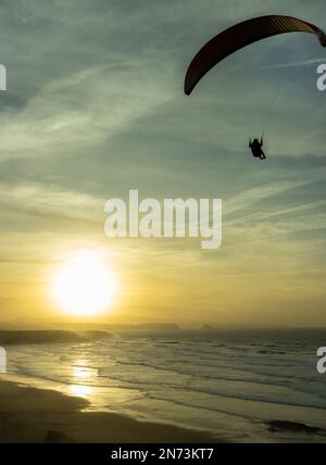 magnifique coucher de soleil sur la plage avec un homme volant sur un parapente Banque D'Images