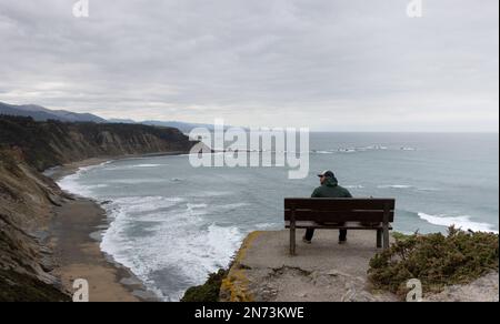 Homme avec Cap regarde l'horizon dans un beau paysage avec la mer et les montagnes. Banque D'Images