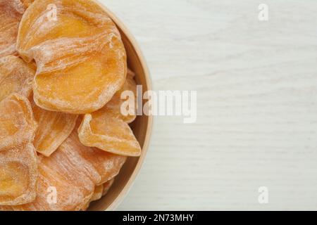 Délicieuses tranches de jackfruit séchées dans un bol sur une table en bois blanc, vue de dessus. Espace pour le texte Banque D'Images