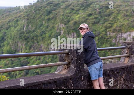 Une jeune femme qui bénéficie d'une vue panoramique sur le parc national des Gorges de la rivière Noire, le point de vue des Gorges à Maurice. Elle couvre une superficie de 67,54 km, y compris une forêt humide de hautes terres, une forêt plus sèche de basses terres et une lande marécageuse. Banque D'Images