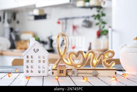 La clé de la maison de la maison confortable avec la décoration de Saint-Valentin sur la table de la cuisine. Cadeau pour la Saint Valentin, nid d'amour familial. Construction, conception, projet, déménagement à ne Banque D'Images