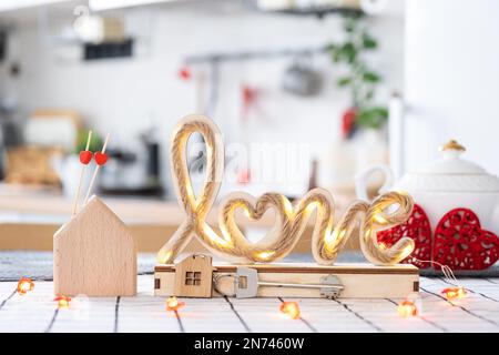 La clé de la maison de la maison confortable avec la décoration de Saint-Valentin sur la table de la cuisine. Cadeau pour la Saint Valentin, nid d'amour familial. Construction, conception, projet, déménagement à ne Banque D'Images