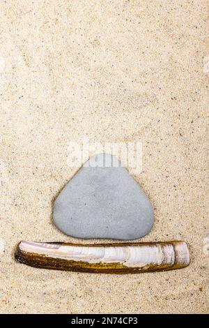 Une coquille de fourreau en forme d'épée et une pierre forment ensemble un voilier, un concept créatif au bord de la mer, encore la vie Banque D'Images