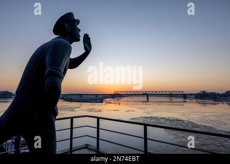 La statue de bronze « l'appelant » au lever du soleil en hiver à Lauenburg/Elbe avec vue sur le pont d'Elbe Banque D'Images