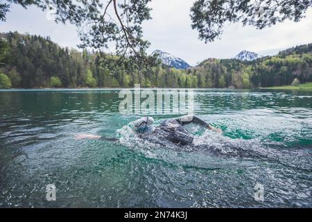 Natation professionnelle triathlète, entraînement dans un lac de montagne clair à Allgäu, Alatsee, Bavière, Allemagne Banque D'Images