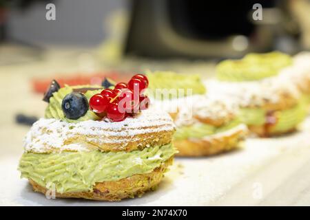 Paris Brest, un dessert français classique se compose d'une grande bague de pâte de choux cuite au four, remplie de pistache douce et de crème de noisette surmontée de P rôti Banque D'Images