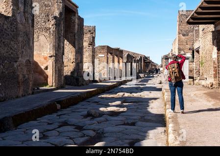 Pompéi, en Italie, Un touriste sur une route pavée romaine typique de l'ancienne Pompéi, dans le sud de l'Italie Banque D'Images