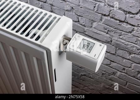 Thermostat de radiateur WLAN FRITZ! DECT 302, affichage de 2ö°C., technologie Smart Home, image d'icône, mise en réseau, numérique, coûts énergétiques, augmentation des coûts de chauffage, arrière-plan mur de brique blanche, Banque D'Images