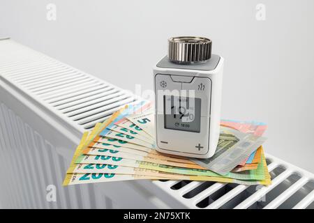Thermostat de radiateur WLAN FRITZ! DECT 302, factures en euros sur radiateur, fond blanc, image d'icône, remplacer le thermostat de chauffage, économiser de l'énergie, Banque D'Images