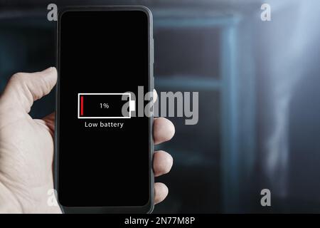 Gros plan d'un smartphone avec une icône de batterie faible sur l'écran indiquant que le niveau de la batterie est à un pour cent. Batterie déchargée sur mobile Banque D'Images