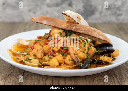 Repas alléchant de cioppino avec de grandes quantités de crevettes, moules, pétoncles et palourdes servis sur une grande assiette. Banque D'Images