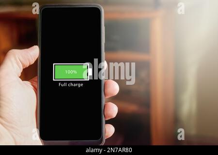 Gros plan sur un smartphone avec une icône de batterie pleine à l'écran indiquant que le niveau de la batterie est à 100 %. Charge complète ba Banque D'Images