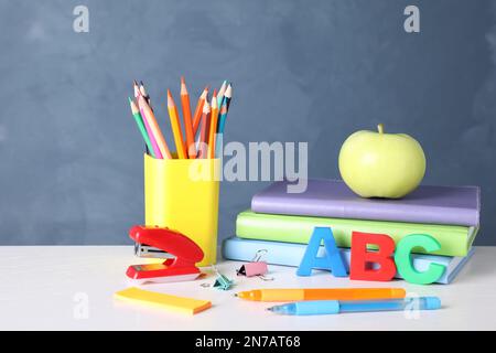 Pomme et différentes fournitures scolaires sur table en bois blanc Banque D'Images