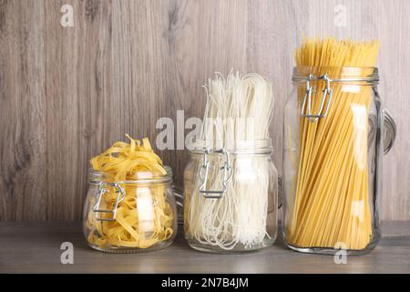 Différents types de pâtes dans des pots en verre sur une table en bois Banque D'Images
