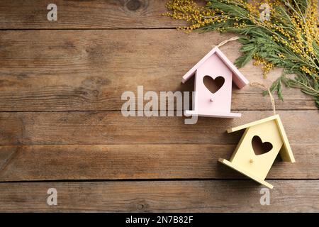 Belles maisons d'oiseaux avec trous en forme de coeur et fleurs mimosa sur fond de bois, espace pour le texte. Composition de la pose à plat à ressort Banque D'Images