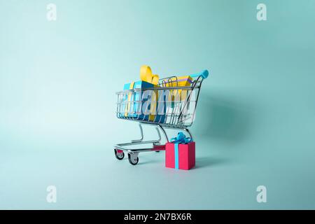 Panier avec un groupe de cadeaux et de cadeaux pour Noël, les anniversaires ou la Saint-Valentin fait de papier coloré sur un fond plat Banque D'Images