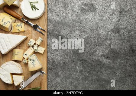 Plateau à fromage avec couteau spécialisé et fourchette sur table grise, plat. Espace pour le texte Banque D'Images