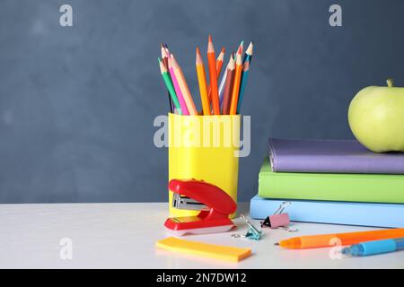 Pomme et différentes fournitures scolaires sur table en bois blanc Banque D'Images