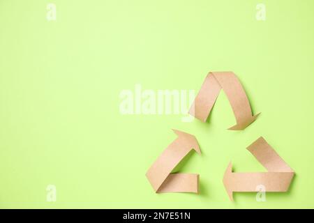 Symbole de recyclage coupé en papier sur fond vert, vue de dessus. Espace pour le texte Banque D'Images