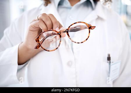 Lunettes, main et vision avec un médecin femme tenant une paire de lunettes de cadre dans une clinique pour la correction de la vue. Soins de santé, médical et assurance avec Banque D'Images