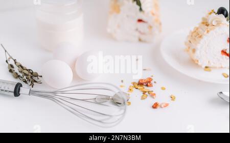 Rouleau de meringue sans sucre sur plaque blanche coupé en morceaux devant une bouteille de lait et d'œufs Banque D'Images