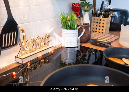 L'intérieur de la cuisine de la maison est décoré de coeurs rouges pour la Saint-Valentin. Décoration sur la table, cuisinière, ustensiles, ambiance festive dans un fari Banque D'Images