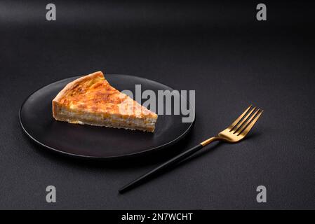 Belle tarte délicieuse à la quiche avec quatre types de fromage aux épices et aux herbes sur fond de béton foncé Banque D'Images