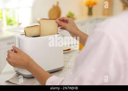 Jeune femme utilisant le grille-pain à la table dans la cuisine, gros plan Banque D'Images