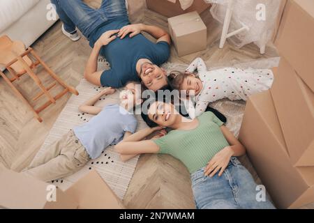 Bonne famille, située à l'étage près des boîtes de déménagement dans la nouvelle maison, vue de dessus Banque D'Images