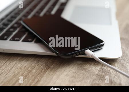 MYKOLAIV, UKRAINE - 28 AOÛT 2020 : iPhone 11, câble de charge et ordinateur portable MacBook sur table en bois Banque D'Images