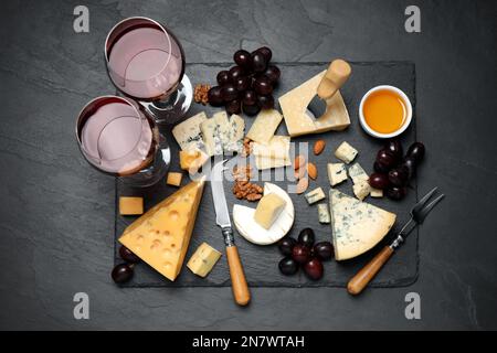 Plateau à fromage avec couteau spécialisé et fourchette sur table noire, plat Banque D'Images