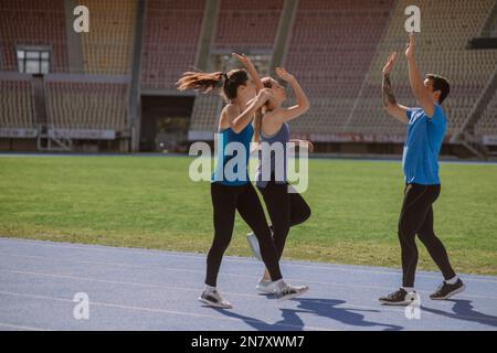 Joyeux sportif masculin donnant cinq hauts à ses amis féminins. Ils se font avec leur formation quotidienne Banque D'Images