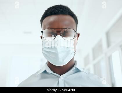 Covid est encore une menace réelle. un beau jeune homme d'affaires éternuant tout en portant un masque dans le bureau. Banque D'Images