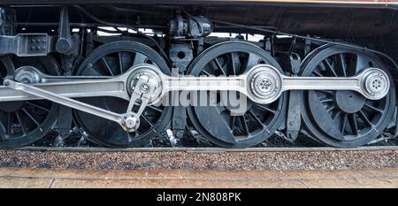 Vue rapprochée des roues motrices en marche d'un train à vapeur d'une ancienne locomotive restaurée Banque D'Images