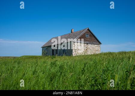 Une ferme de galets abandonnée se dresse dans les prairies de Dickinson, Dakota du Nord, pendant un après-midi d'été. Banque D'Images