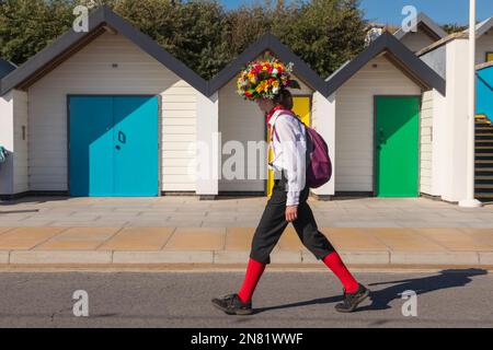 Angleterre, Dorset, Île de Purbeck, Swanage, Swanage Folk Festival, Morris Dancer Marche en face des cabanes de plage colorées Banque D'Images