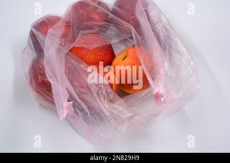 Un grand paquet de fruits, de nourriture saine, beaucoup de pommes rouges mûres se trouvent dans un sac jetable rose. Banque D'Images