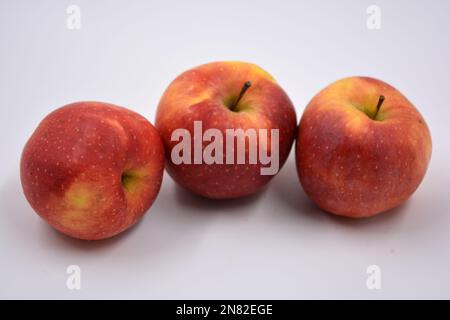 Trois grandes pommes rouges mûres jaunes, fruits doux disposés sur un fond blanc. Banque D'Images