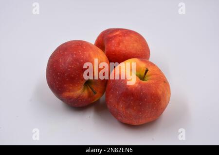 Trois grandes pommes rouges mûres jaunes, fruits doux disposés sur un fond blanc. Banque D'Images