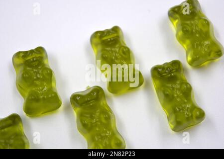 La mastication verte des enfants, les bonbons en gelée sous forme et sous forme d'ours colorés sont situés sur un fond blanc. Banque D'Images