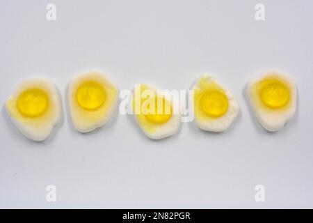 La mastication lumineuse pour enfants, les bonbons en gelée sous forme de nourriture et les œufs brouillés frits sont situés sur un fond blanc. Banque D'Images