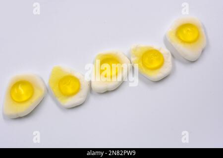 La mastication lumineuse pour enfants, les bonbons en gelée sous forme de nourriture et les œufs brouillés frits sont situés sur un fond blanc. Banque D'Images