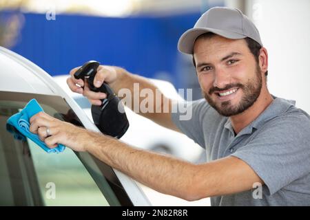 le personnel du service automobile nettoie le pare-brise de la voiture Banque D'Images