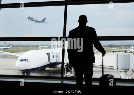 Aéroport, voyage et silhouette homme d'affaires montre vol d'avion, réservation de vol ou transport pour le voyage du monde. Valises, départ de l'aéroport et Banque D'Images