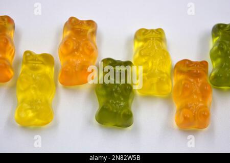 La mastication orange, verte, jaune pour enfants, les bonbons en gelée sous forme et sous forme d'ours colorés sont situés sur un fond blanc. Banque D'Images