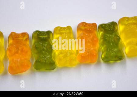 La mastication orange, verte, jaune pour enfants, les bonbons en gelée sous forme et sous forme d'ours colorés sont situés sur un fond blanc. Banque D'Images