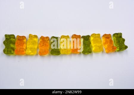 La mastication orange, verte, jaune pour enfants, les bonbons en gelée sous forme et sous forme d'ours colorés sont situés sur un fond blanc. Banque D'Images