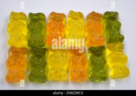 La mastication orange, verte, jaune pour enfants, les bonbons en gelée sous forme et sous forme d'ours colorés sont situés sur un fond blanc. Banque D'Images