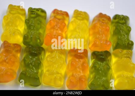 La mastication orange, verte, jaune pour enfants, les bonbons en gelée sous forme et sous forme d'ours colorés sont situés sur un fond blanc. Banque D'Images
